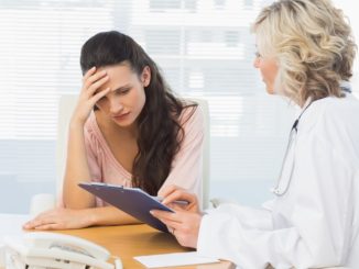 Female doctor discussing reports with patient at desk in medical office