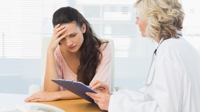 Female doctor discussing reports with patient at desk in medical office